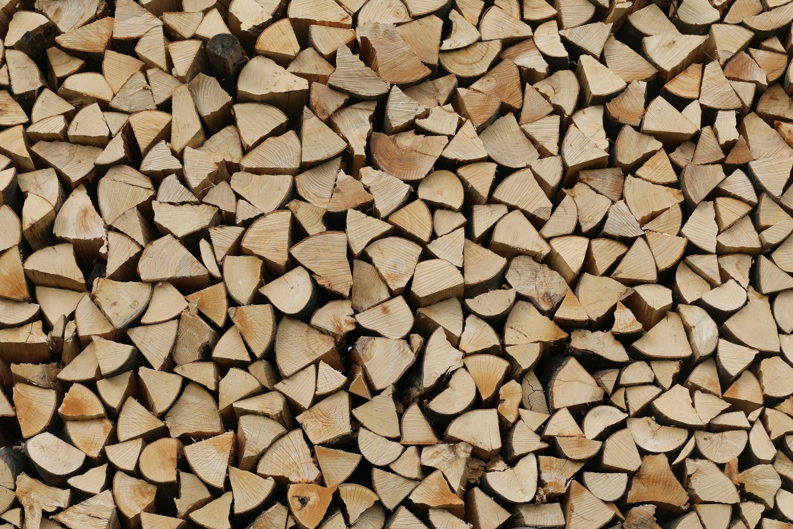 A stacked collection of chopped firewood creates a rustic, textured pattern for use in backgrounds or designs.